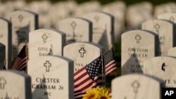 Headstones are decorated with American flags at Leavenworth National Cemetery on the eve of Memorial Day, May 29, 2022, in Leavenworth, Kan. 