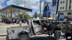A destroyed vehicle is removed from the scene after a suicide bomb attack at a checkpoint near the airport in Mogadishu, Somalia, May 11, 2022. 