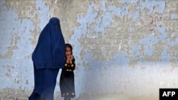 Seorang perempuan mengenakan burqa berjalan bersama seorang anak di Kabul, Afghanistan, pada 7 Mei 2022. (Foto: AFP/Ahmad Sahel Arman)