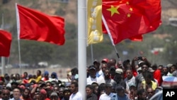 FILE - Spectators hold a Chinese flag as they watch a ceremony to mark the opening of Independence Drive Boulevard in Port Moresby, Papua New Guinea, Friday, Nov. 16, 2018. (AP Photo/Mark Schiefelbein, Pool, File)