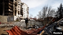 7일 우크라이나 수도 크이우의 러시아 군의 폭격을 받은 잔해에서 전범 검사단이 전화 통화를 하고 있다. 