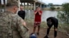 Three migrants from Cuba stand in front of a National Guardsman after crossing the Rio Grande river in Eagle Pass, Texas, May 22, 2022.