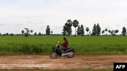 រូបឯកសារ៖ ស្ត្រីម្នាក់កំពុងបើកម៉ូតូ កាត់ផ្លូវក្នុងភូមិមួយ នៅខេត្តសៀមរាប កាលពីថ្ងៃទី ១៥ ខែតុលា ឆ្នាំ ២០២០។