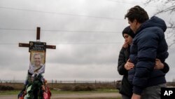FILE - Yura Nechyporenko, 15, hugs his uncle Andriy Nechyporenko above the grave of his father Ruslan Nechyporenko at the cemetery in Bucha, on the outskirts of Kyiv, Ukraine, on April 21, 2022.