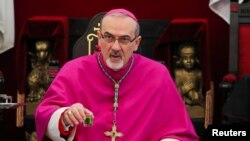 FILE - Pierbattista Pizzaballa, the Latin Patriarch of Jerusalem, waits before crossing into Israeli-occupied West Bank town of Bethlehem to attend Christmas celebrations, in Jerusalem, Dec. 24, 2021.