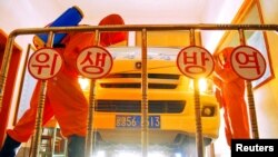 23일 북한 평양에서 방역 요원들이 자동차를 소독하고 있다. KCNA via REUTERS.