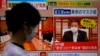 A passerby walks past a screen displaying an image of North Korean leader Kim Jong Un wearing a face mask on a TV news program in Tokyo, May 13, 2022.