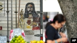A woman walks past a fruit vendor at a street market in Rio de Janeiro, Brazil, May 11, 2022. High inflation in Brazil is eroding the buying power of consumers and angering potential voters, who fault President Jair Bolsonaro for not doing enough about it.