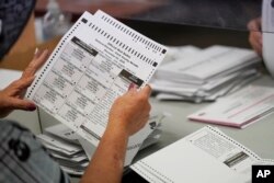 FILE - County employees process mail-in ballots at a Clark County election department facility in Las Vegas, Nevada, Oct. 31, 2020.
