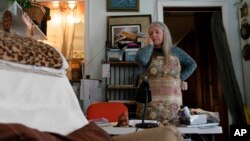 FILE - Nancy Rose, who contracted COVID-19 in 2021 and continues to exhibit long-haul symptoms including brain fog and memory difficulties, pauses while organizing her desk space, in Port Jefferson, New York, Jan. 25, 2022.