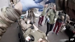 Yuliia Paievska, known as Taira, assists as a serviceman is brought in on a stretcher on Feb. 24, 2022, in Mariupol. Using a body camera, she recorded her team's frantic efforts to bring people back from the brink of death. (Yuliia Paievska via AP)