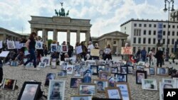 This photo provided by Syrian activist Wafaa Mustafa, shows families of Syrian detainees carrying photos of their detained the missing loved ones, as they demanding their freedom and the revealing of their fate and whereabouts during a sit-in, in Berlin, May, 7, 2022.