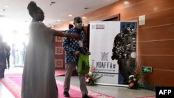 Une hôtesse dirige les visiteurs à l'entrée de la 14e édition de la Biennale d'art contemporain africain, le 19 mai 2022, au grand théâtre Doudou Ndiaye Coumba Rose.