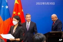 Menteri Luar Negeri China Wang Yi, tengah, tampil di atas panggung pada pertemuan Menteri Luar Negeri Kepulauan Pasifik dengan Perdana Menteri Fiji Frank Bainimarama, Senin, 30 Mei 2022, di Suva, Fiji. (Foto: via AP)