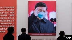 In this picture taken on January 15, 2021, a picture of China's President Xi Jinping with a face mask is displayed as people visit an exhibition about China's fight against the COVID-19 coronavirus.