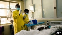 Des infirmières s'occupent d'un patient allongé sur un lit d'hôpital dans un service médical d'un hôpital local à Harare le 26 avril 2022.