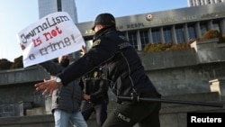 FILE - Police officers restrain a protester during a rally by journalists against a new media bill, in front of the Parliament building in Baku, Azerbaijan, Dec. 28, 2021.