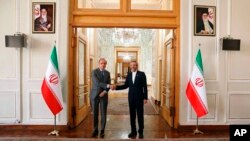 In this photo released by the Iranian Foreign Ministry, Enrique Mora, the European Union coordinator of talks to revive Iran's nuclear accord with world powers, left, shakes hands with Iran's top nuclear negotiator Ali Bagheri Kani, in Tehran, Iran, May 11, 2022.