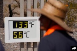 People visit a thermometer July 11, 2021, in Death Valley National Park, Calif.