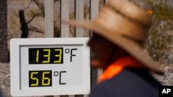 People visit a thermometer July 11, 2021, in Death Valley National Park, Calif.