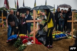 People attend the funeral service for 47-year-old Olexandr Haponchev, a Ukrainian serviceman killed during the Russian invasion of Ukraine, in the military section of Kharkiv cemetery number 18 in Bezlioudivka, eastern Ukraine, May 21, 2022.