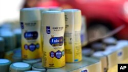 Infant formula is stacked on a table during a baby formula drive to help with the shortage, May 14, 2022, in Houston. 