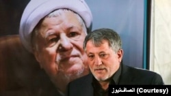 محسن هاشمی در کنار عکس پدرش اکبر هاشمی رفسنجانی