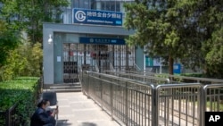 A worker sits near the closed exit of a subway station in Beijing, May 4, 2022. Shanghai has been under lockdown since late March to reduce the spread of COVID.