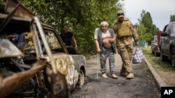 Volonter pomaže starijem čoveku da se evakuiše iz zgrade oštećene u ruskom napadu na Slovjansk(Foto:AP/Francisco Seco)