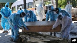 FILE - Health workers and relatives move a casket with the body of a COVID-19 victim for cremation, in Jammu, India, April 25, 2021.