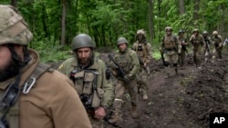 Ukrainian servicemen walk in the forest near a recently retaken village, north of Kharkiv, east Ukraine, May 15, 2022. (AP Photo/Mstyslav Chernov)