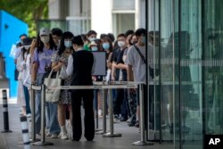 Employees wearing face masks wait to have their COVID-19 test results checked to enter an office building in the central business district in Beijing, Tuesday, May 31, 2022. (AP Photo/Mark Schiefelbein)