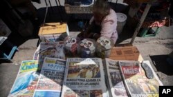 FILE - A newspaper saleswoman waits for customers in San Salvador, El Salvador, Feb. 10, 2020. 