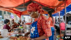 Une femme sert un thieboudiene, également connu sous le nom de Ceebu Jën (littéralement "riz au poisson" en wolof) près du marché de Kermel à Dakar le 14 décembre 2021. (Photo CARMEN ABD ALI / AFP)