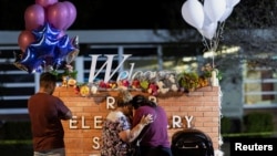 FILE - Elida Gonzales clings to her daughter, Amber Gonzales, as Amber Gonzales’ husband, Albert Martinez, looks on at a memorial set up outside Robb Elementary School, the site of a mass shooting, in Uvalde, Texas, May 25, 2022.