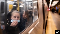 FILE - A passenger looks out onto the platform while riding a northbound train in the 36th Street subway station during the morning commute, in New York, April 13, 2022. 