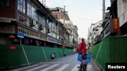 Seorang pekerja delivery mengantar makanan di kawasan Shanghai yang tengah memberlakukan lockdown (9/5) (foto: ilustrasi). 