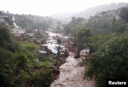 A river runs high after heavy rains, next to homes which were damaged during previous flooding, in kwaNdengezi near Durban, South Africa, May 22, 2022.