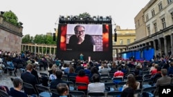 FILE - Spectators attend the award ceremony at the 71st Berlinale Summer Festival at the open-air cinema Museum Island. A photo of Mohammad Rasoulof of Iran, a member of the 2021 International Jury, can be seen on the big screen in Berlin, Germany, June 1