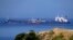 The Pegas tanker, that has recently changed its name to Lana, foreground, is seen off the port of Karystos on the Aegean Sea island of Evia, Greece, May 27, 2022. Greece’s armed forces are on high alert in the Eastern Aegean Sea as tensions escalate with Turkey.