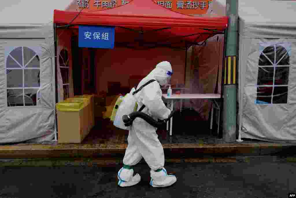 A worker wearing personal protective equipment disinfects the entrance to a residential area on lockdown due to the recent COVID-19 outbreaks in Beijing.