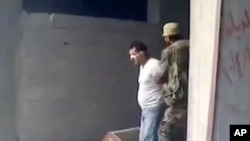 This frame grab from a 2013 video, shows Syrian Wassim Siyam blindfolded being forced into a large pit full of bodies and shot dead by a Syrian soldier, in the Tadamon neighborhood of Damascus, Syria.