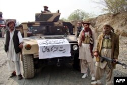 FILE - Armed militants of Tehrik-i-Taliban Pakistan pose for photographs next to a captured armored vehicle in the Pakistan-Afghanistan border town of Landikotal on Nov. 10, 2008.