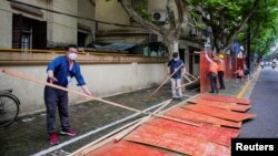 上海工人在拆除封闭街道的围栏。（2022年5月30日）