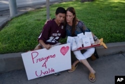 Diego Esquivel, kiri, dan Linda Klaasson saling menghibur saat menghormati para korban tewas dalam penembakan Selasa di Sekolah Dasar Robb di Uvalde, Texas, Rabu, 25 Mei 2022. (Foto: AP)