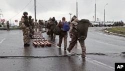 Dalam potongan gambar yang diambil dari video milik Kementerian Pertahanan Rusia pada 19 Mei 2022, para tentara Ukraina, kanan, meninggalkan pabrik baja Azovstal di Mariupol, Ukraina. (Foto: Russian Defense Ministry Press Service via AP)