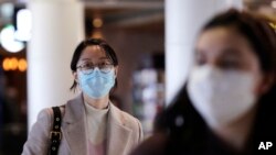 Travelers at Seattle-Tacoma International Airport wear masks Tuesday, March 3, 2020, in SeaTac, Wash. Six of the 18 Western Washington residents with the coronavirus have died as health officials rush to test more suspected cases and communities…