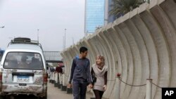 Pasangan Mesir berjalan di pembatas beton yang mengelilingi Departemen Luar Negeri di Kairo, Mesir, Kamis, 27 November 2014.