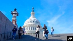 Dengan latar belakang US Capitol, orang-orang berjalan menuruni tangga pada Hari Pemilihan di Washington, Selasa, 8 November 2022. (Foto: AP/Mariam Zuhaib)