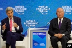 FILE - John Kerry, Special Presidential Envoy for Climate of the United States, left, gestures besides Xie Zhenhua, Special Envoy for Climate Change of the People's Republic of China, during the World Economic Forum in Davos, Switzerland, May 24, 2022.